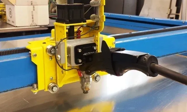 A yellow machine is cutting metal with a black handle.