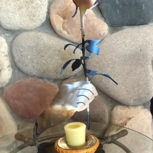 A candle is lit on the table by a stone wall.