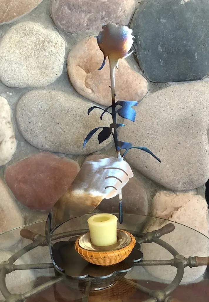 A candle is lit on the table by a stone wall.
