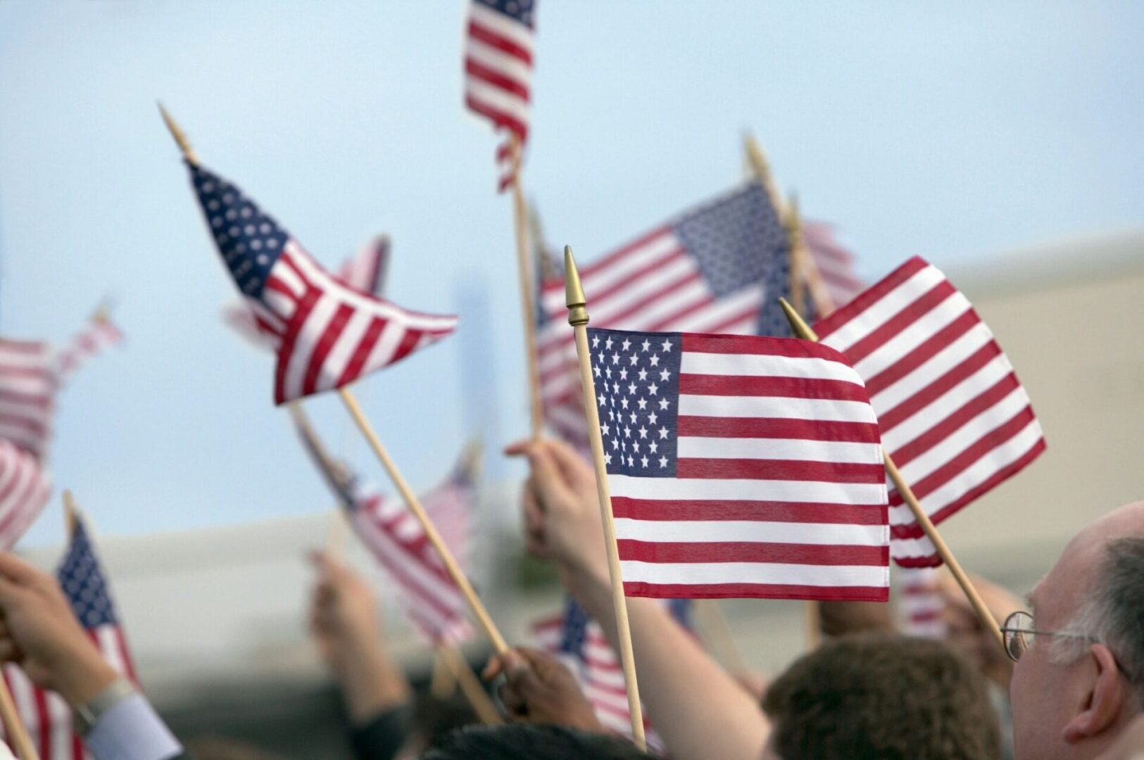 A group of people holding american flags in the air.